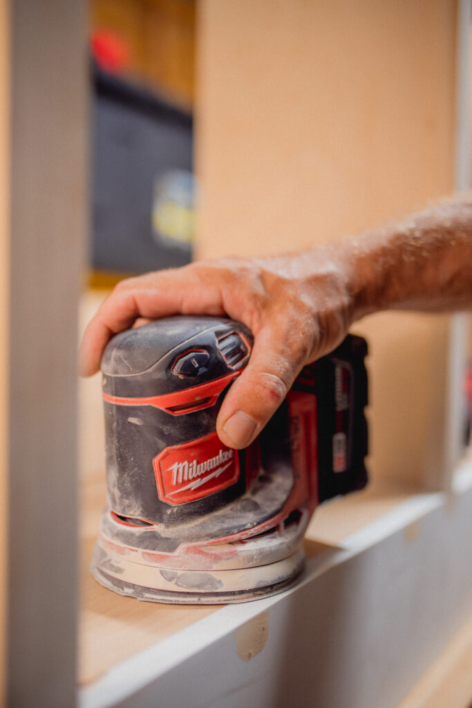 Close-up of Dustin Dalton sanding a custom woodworking project with a Milwaukee sander.